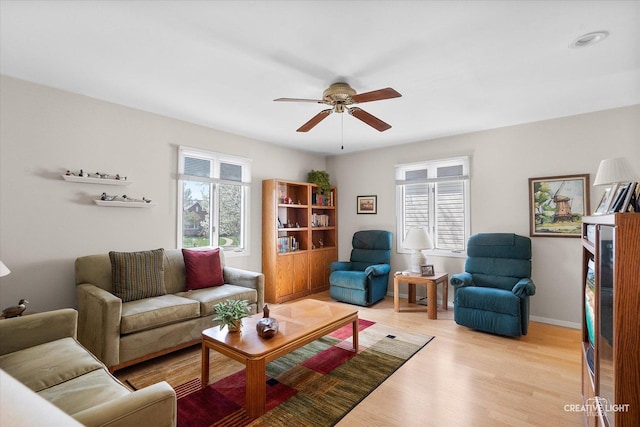 living room with light wood-style floors, ceiling fan, and a healthy amount of sunlight