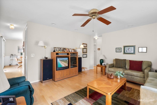 living room featuring ceiling fan, baseboards, and light wood finished floors