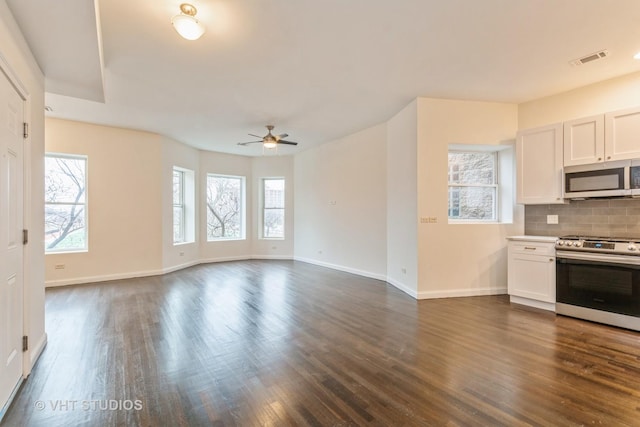 kitchen with dark wood-style flooring, appliances with stainless steel finishes, a ceiling fan, baseboards, and backsplash