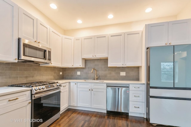 kitchen featuring appliances with stainless steel finishes, a sink, light countertops, tasteful backsplash, and dark wood-type flooring