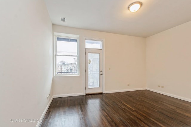 unfurnished room featuring baseboards, dark wood-type flooring, and visible vents