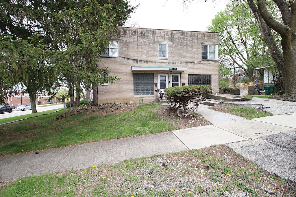 view of front of home with brick siding, a front lawn, and concrete driveway