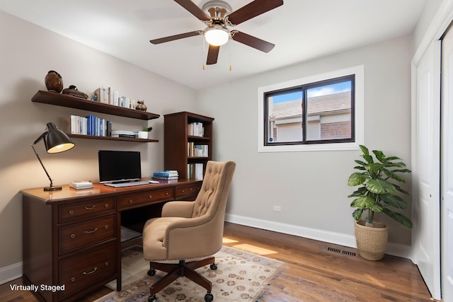 office space featuring visible vents, a ceiling fan, baseboards, and wood finished floors