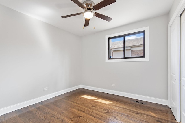 unfurnished room featuring baseboards, ceiling fan, dark wood finished floors, and visible vents