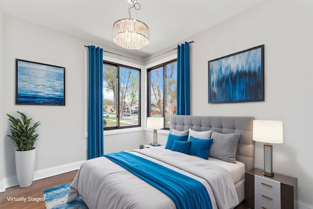 bedroom with an inviting chandelier, baseboards, and wood finished floors