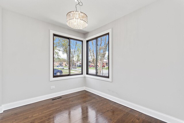 unfurnished dining area with visible vents, baseboards, dark wood-type flooring, and a notable chandelier