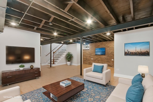 tiled living room featuring baseboards, brick wall, and stairway