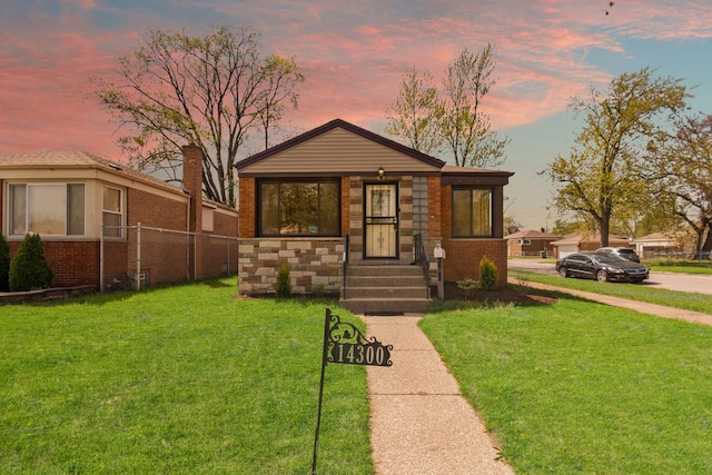 bungalow-style home with fence, a front yard, and brick siding