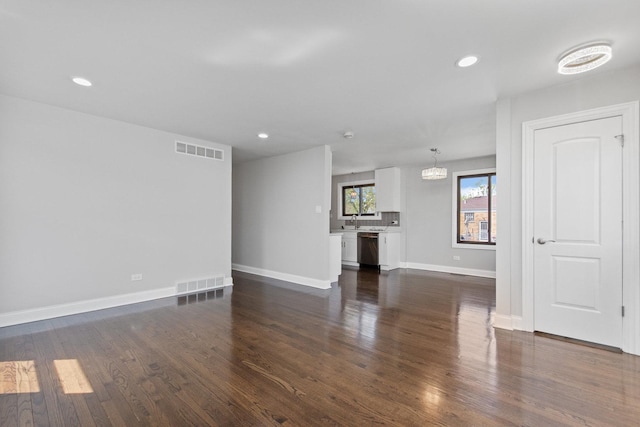 unfurnished living room featuring dark wood-style flooring, baseboards, visible vents, and recessed lighting