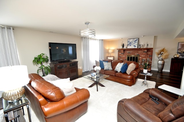 living room with baseboards, a brick fireplace, and wood finished floors