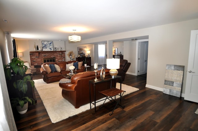 living area with baseboards, a brick fireplace, and wood finished floors