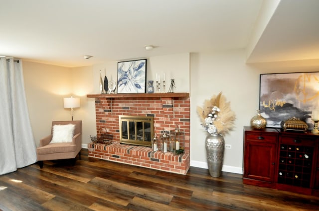 living area with baseboards, a brick fireplace, and wood finished floors