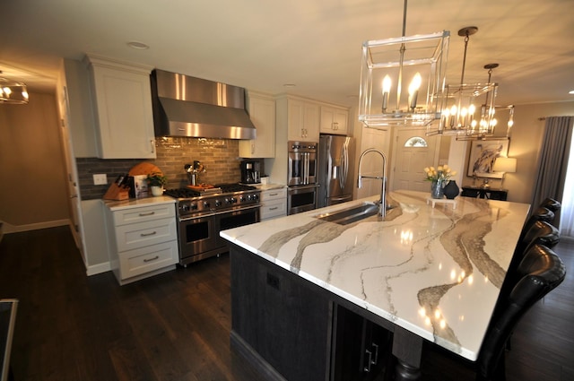 kitchen with stainless steel appliances, a chandelier, a sink, and wall chimney exhaust hood