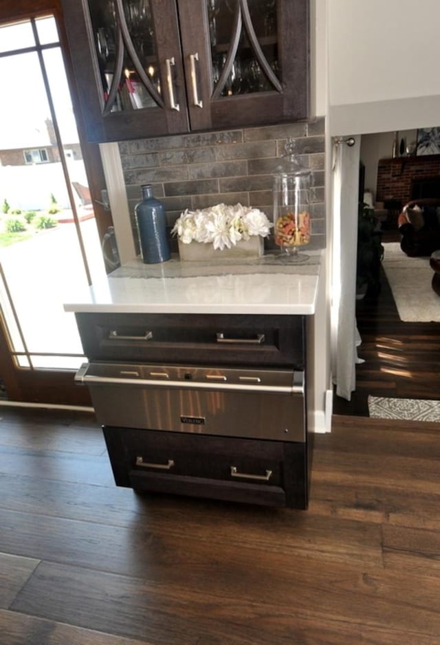 details with light countertops, dark wood-style flooring, backsplash, and dark brown cabinetry