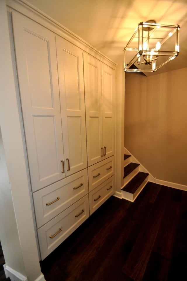 walk in closet featuring an inviting chandelier and dark wood-type flooring