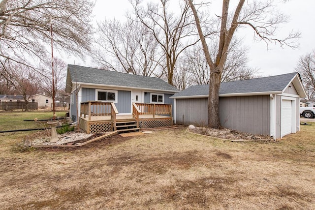 rear view of house featuring a detached garage, a wooden deck, an outbuilding, a chimney, and a yard