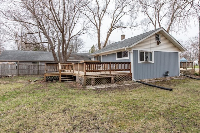rear view of property featuring fence, a yard, a chimney, and a deck