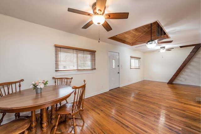 dining room featuring a raised ceiling, ceiling fan, baseboards, and hardwood / wood-style flooring