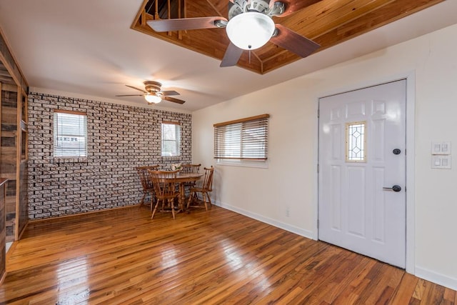 dining area featuring a ceiling fan, brick wall, and wood finished floors