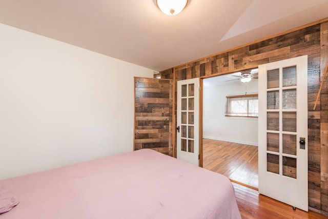 bedroom with wooden walls, french doors, wood finished floors, and lofted ceiling