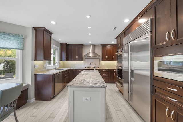 3130 Kayjay Dr, Northbrook, IL 60062 - kitchen with light wood finished floors, a sink, wall chimney exhaust hood, a center island with sink, and built in appliances