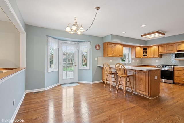 354 Gateshead Dr, Naperville, IL 60565 - kitchen with baseboards, white microwave, stainless steel gas range, a chandelier, and tasteful backsplash