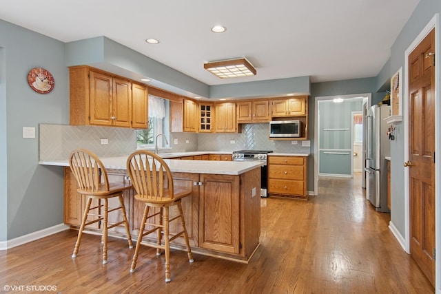 354 Gateshead Dr, Naperville, IL 60565 - kitchen featuring a peninsula, baseboards, light countertops, light wood-style flooring, and appliances with stainless steel finishes