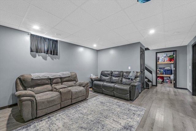 living room with wood finished floors, baseboards, and a paneled ceiling