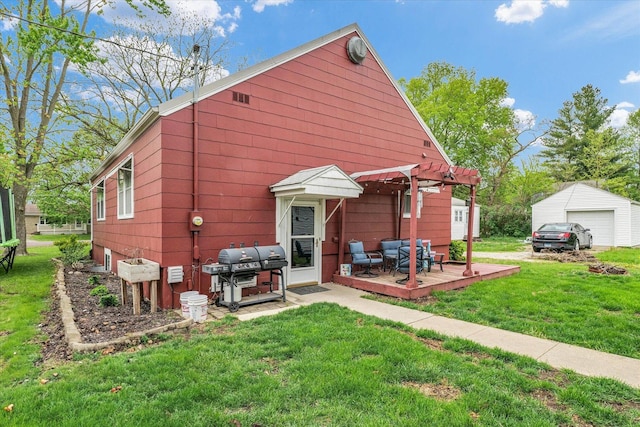 back of house with a yard, an outdoor structure, a garage, a pergola, and a deck