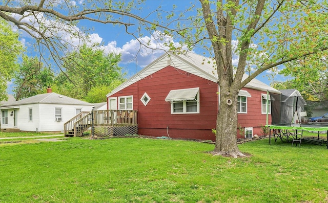 back of house with a lawn, a trampoline, and a deck