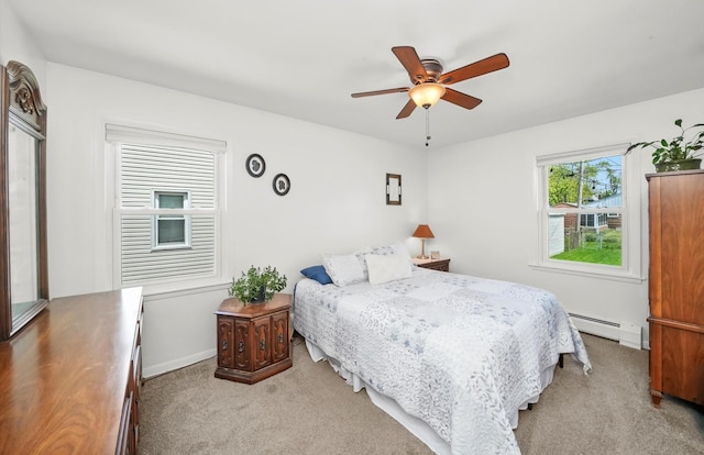 bedroom with a baseboard heating unit, light colored carpet, ceiling fan, and baseboards