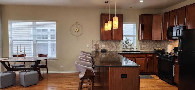 kitchen with plenty of natural light, a sink, black appliances, and a breakfast bar