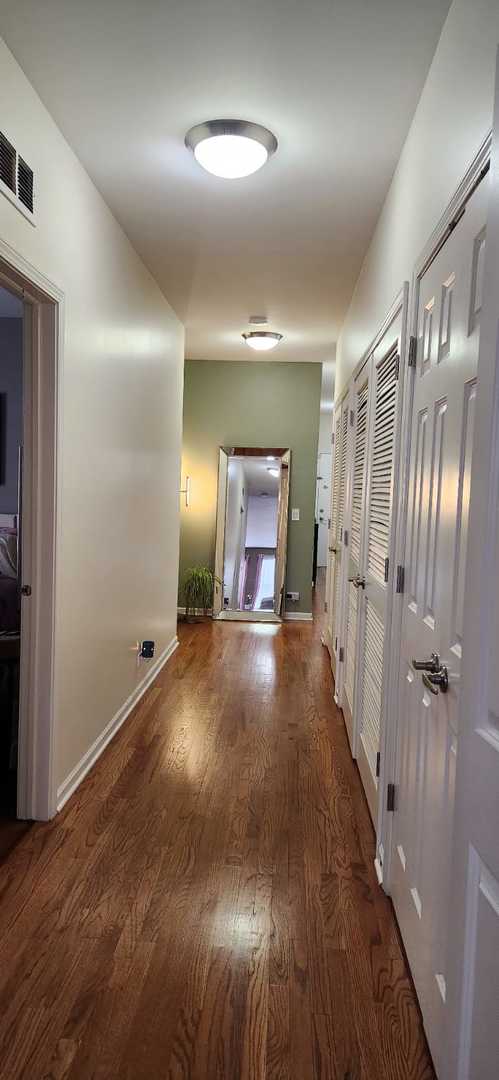 hallway featuring visible vents, baseboards, and wood finished floors