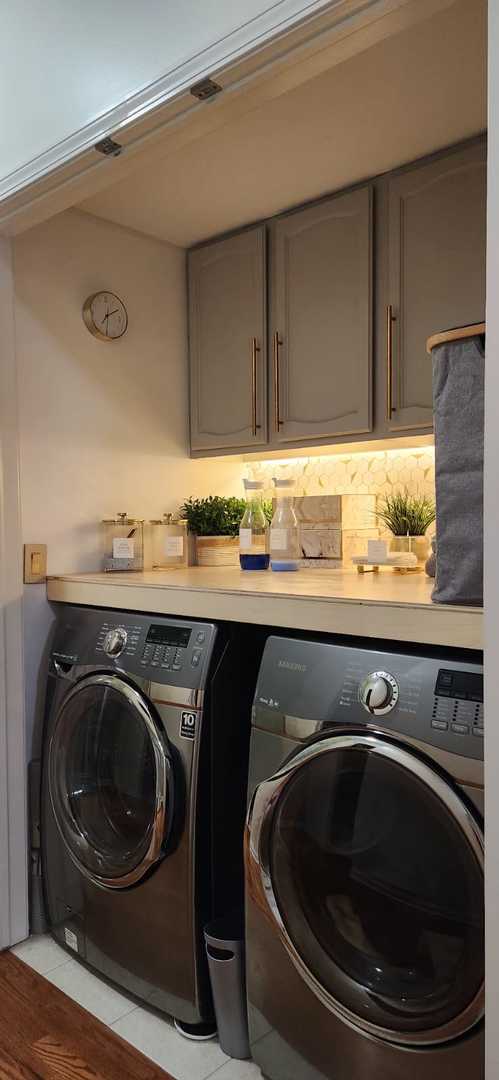 clothes washing area featuring separate washer and dryer and cabinet space