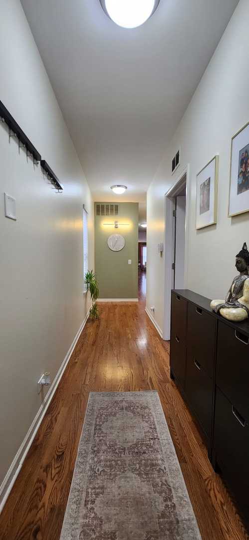 hallway with baseboards, visible vents, and wood finished floors