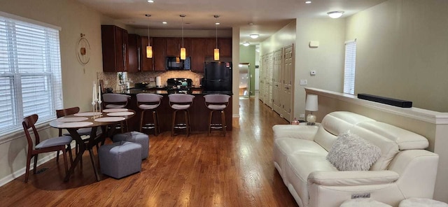living area with baseboards, recessed lighting, and wood finished floors
