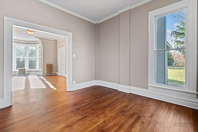 unfurnished room featuring crown molding, radiator, wood-type flooring, plenty of natural light, and baseboards