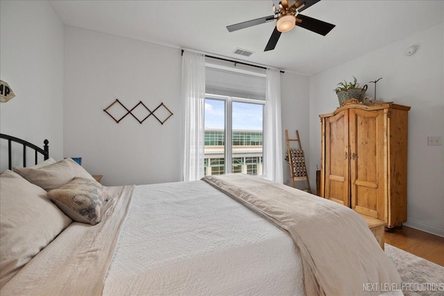 bedroom featuring baseboards, a ceiling fan, wood finished floors, and visible vents