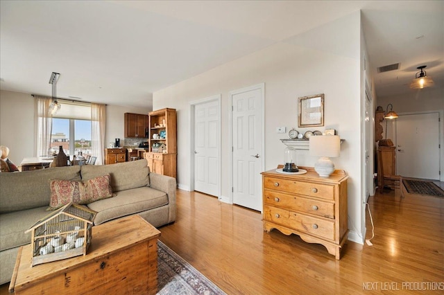 living area with baseboards, visible vents, and light wood-style floors