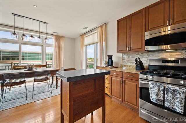 kitchen with appliances with stainless steel finishes, decorative backsplash, light wood-style flooring, and visible vents