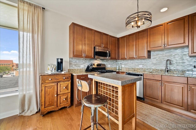kitchen featuring a sink, tasteful backsplash, light wood-style floors, and stainless steel appliances