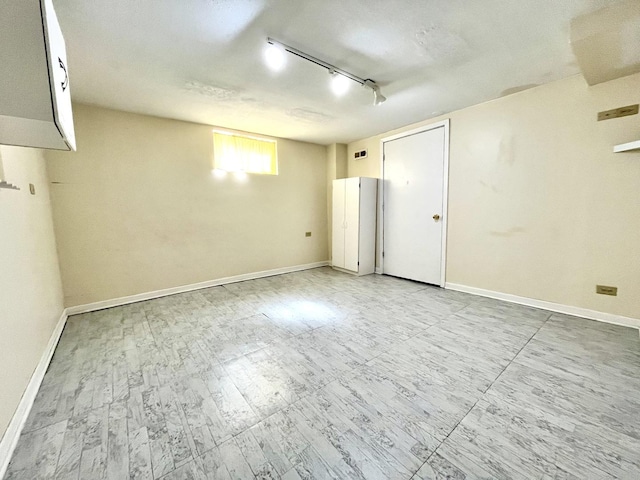 empty room with track lighting and baseboards