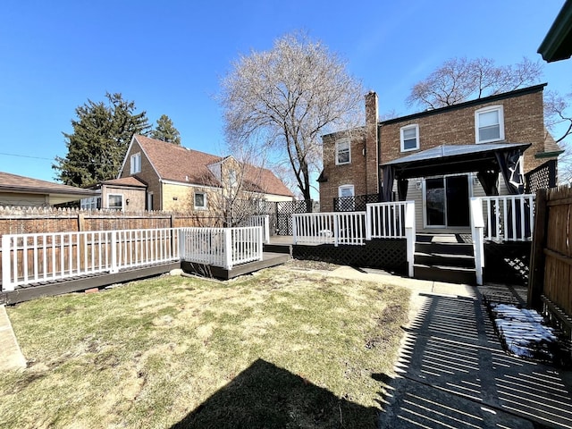 back of house featuring a chimney, a deck, brick siding, a gazebo, and fence