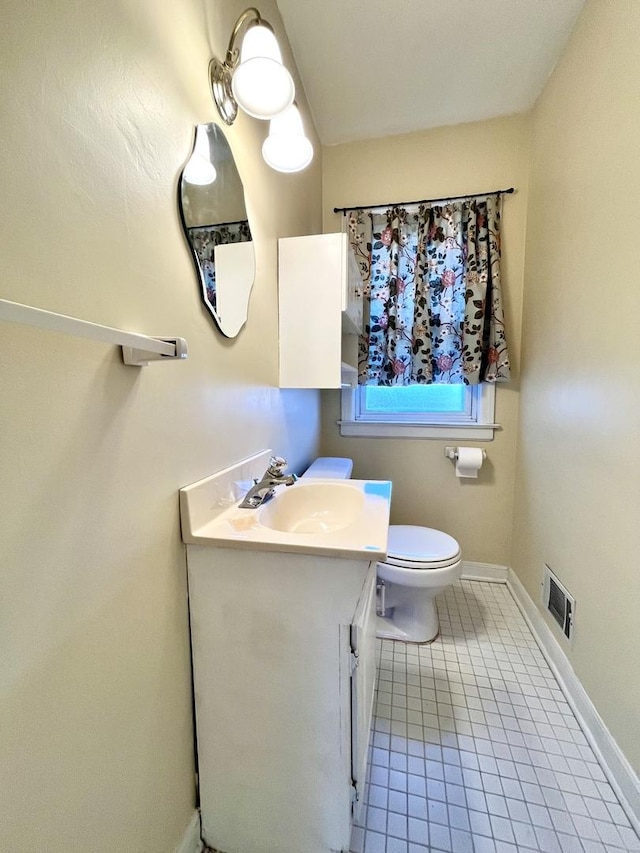 half bathroom featuring tile patterned flooring, vanity, toilet, baseboards, and visible vents