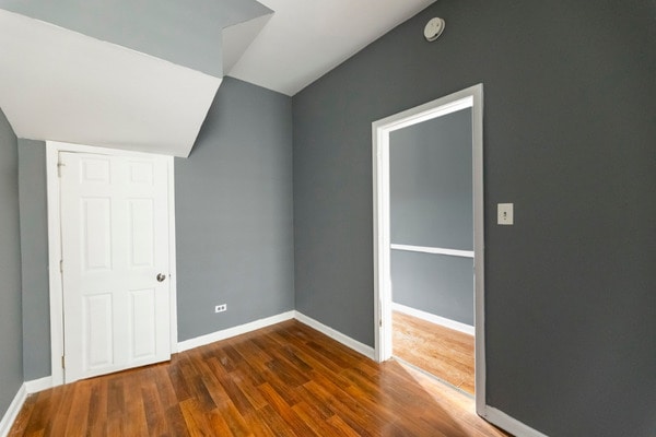 6601 S St Lawrence Ave, Chicago, IL 60637 - unfurnished bedroom with vaulted ceiling, wood finished floors, and baseboards