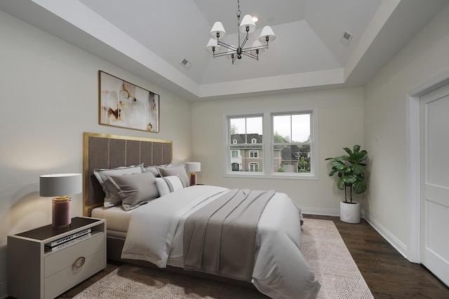 bedroom with visible vents, baseboards, a raised ceiling, dark wood finished floors, and a notable chandelier