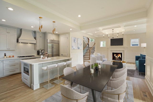 kitchen featuring premium range hood, gray cabinets, built in appliances, and a decorative wall