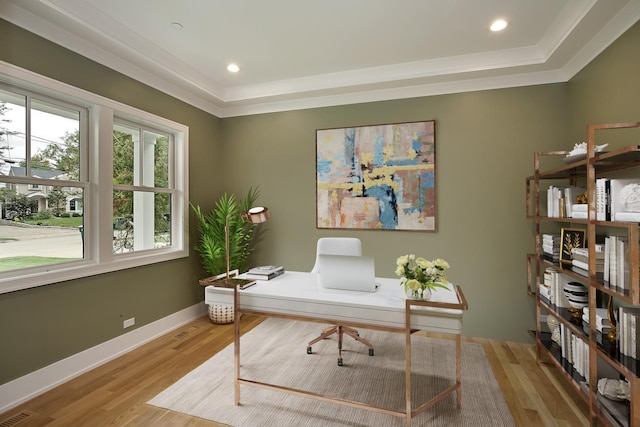 home office with crown molding, a raised ceiling, light wood-style flooring, and baseboards