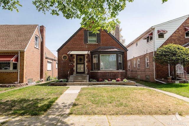 view of front of home with brick siding, a front lawn, and a chimney