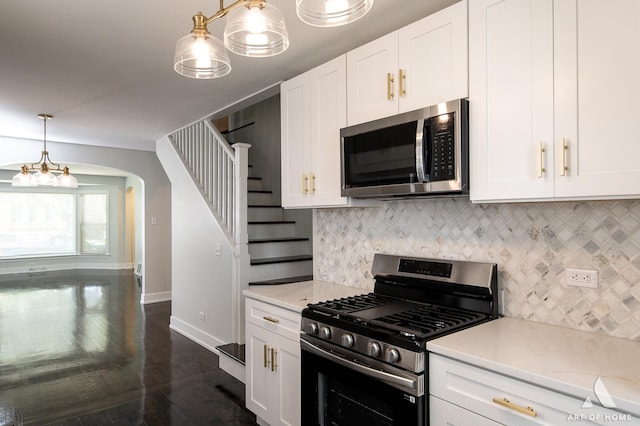 kitchen with arched walkways, white cabinets, baseboards, and stainless steel appliances